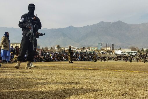Ein Sicherheitsbeamter der Taliban steht Wache, während Menschen in einem Fußballstadion in der Stadt Charikar in der Provinz Parwan am 8. Dezember 2022 der öffentlichen Auspeitschung von Frauen und Männern beiwohnen. © AFP via Getty Images