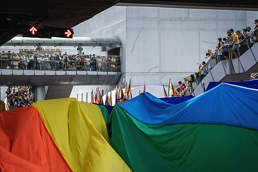 Die Teilnehmenden der Bangkok Pride Parade 2023 tragen an der Pathumwan-Kreuzung eine riesige Regenbogenflagge.